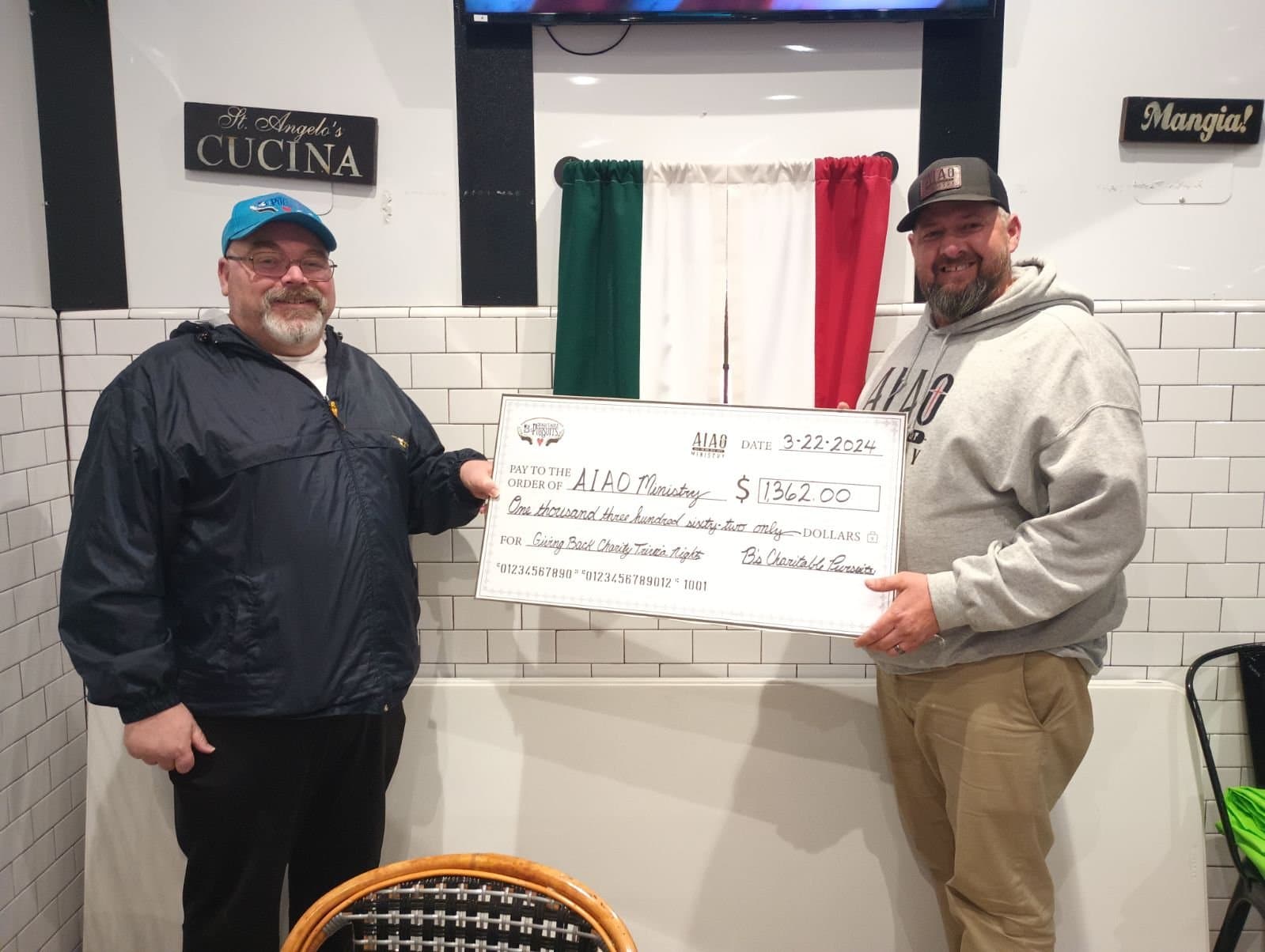 Two men holding an oversized check made out to All In or All Out Ministry.