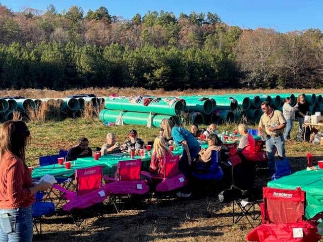 People gathered outdoors at a party with long tables and chairs.
