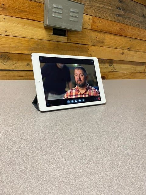 A tablet displaying a man with a beard during a recording session.