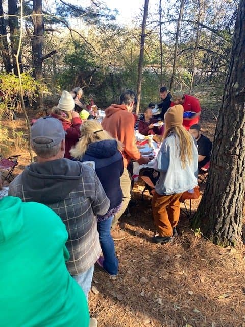 Group gathered around a table outdoors sharing a meal together
